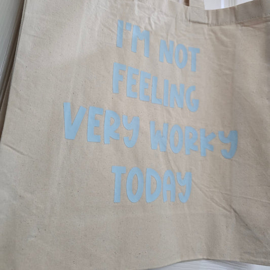 Beige tote bag with blue text 'I'm not feeling very wokey today' on a white background