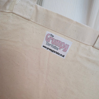 Close-up of a beige bag with a 'Grumpy' label on a white background