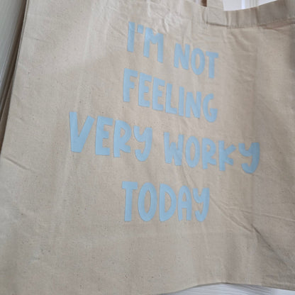 Beige tote bag with blue text 'I'm not feeling very wokey today' on a white background